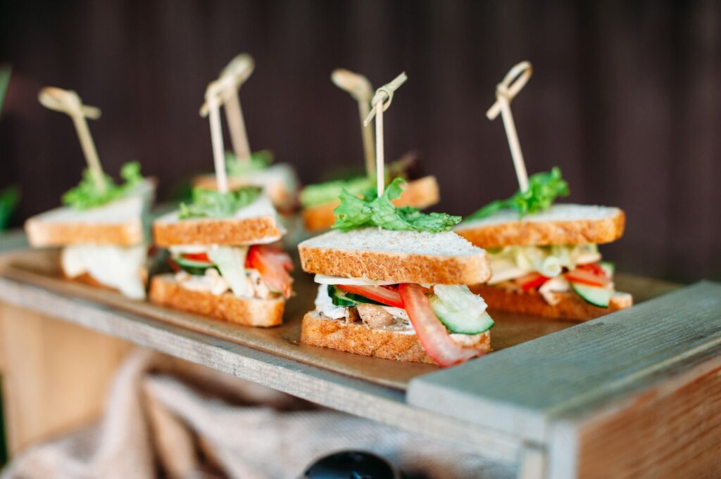 Row of sandwiches with cheese, chicken and vegetables. Catering table for barbecue party
