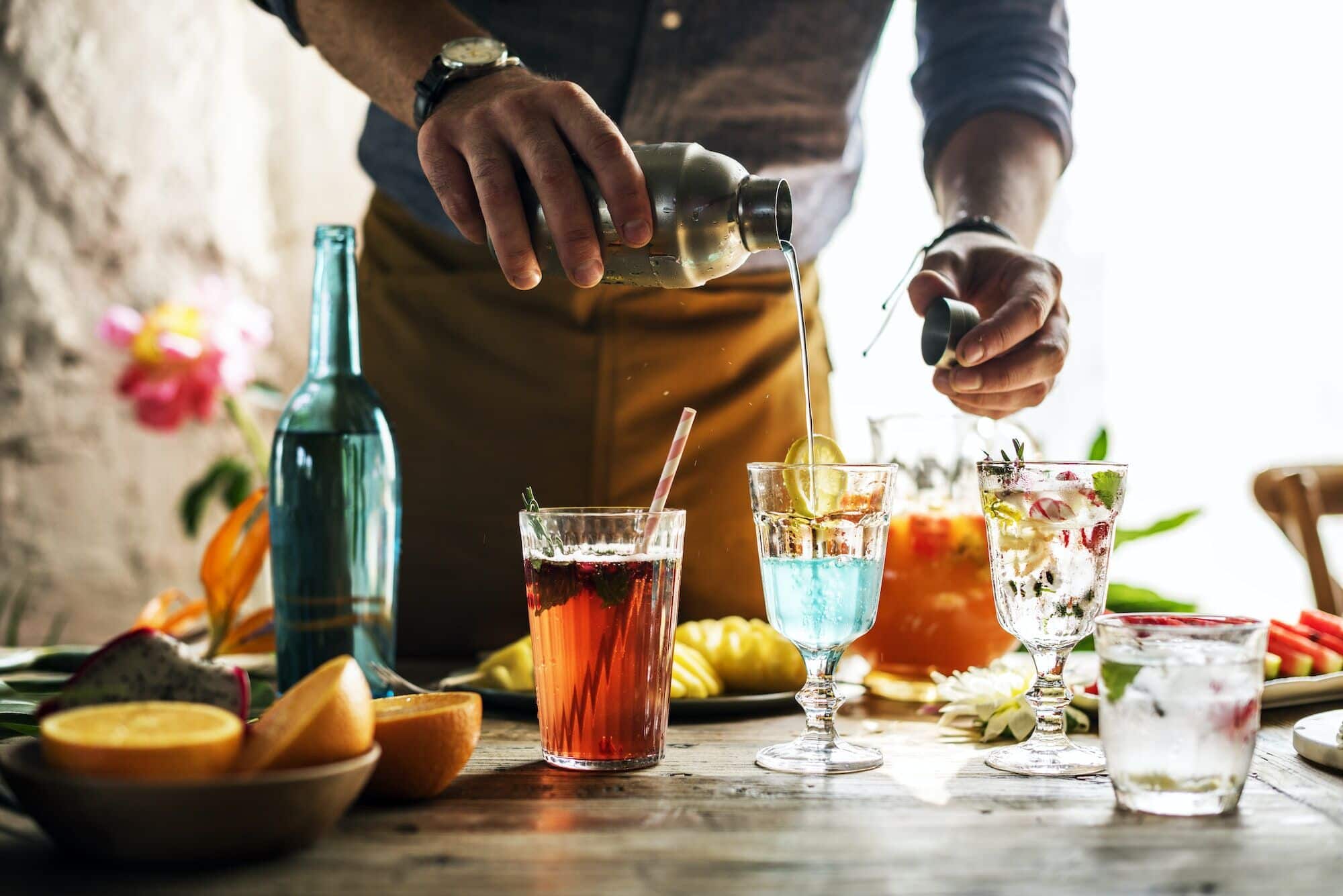 London party bartender mixing colourful cocktails behind the bar