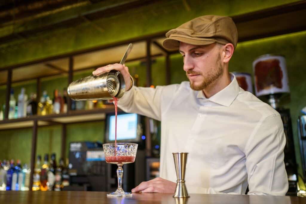 Barman pouring cocktail into glass
