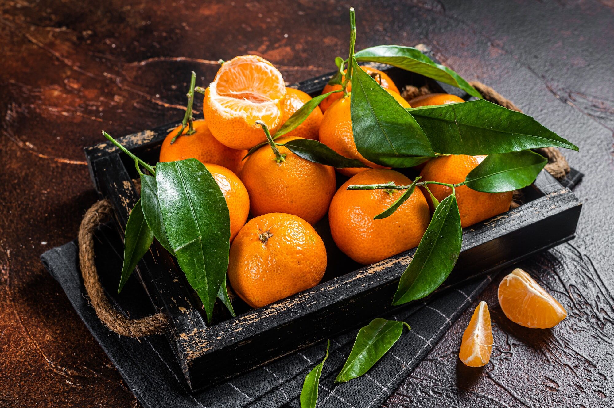 Fresh mandarin oranges or tangerines fruits with leaves. Dark background. Top view