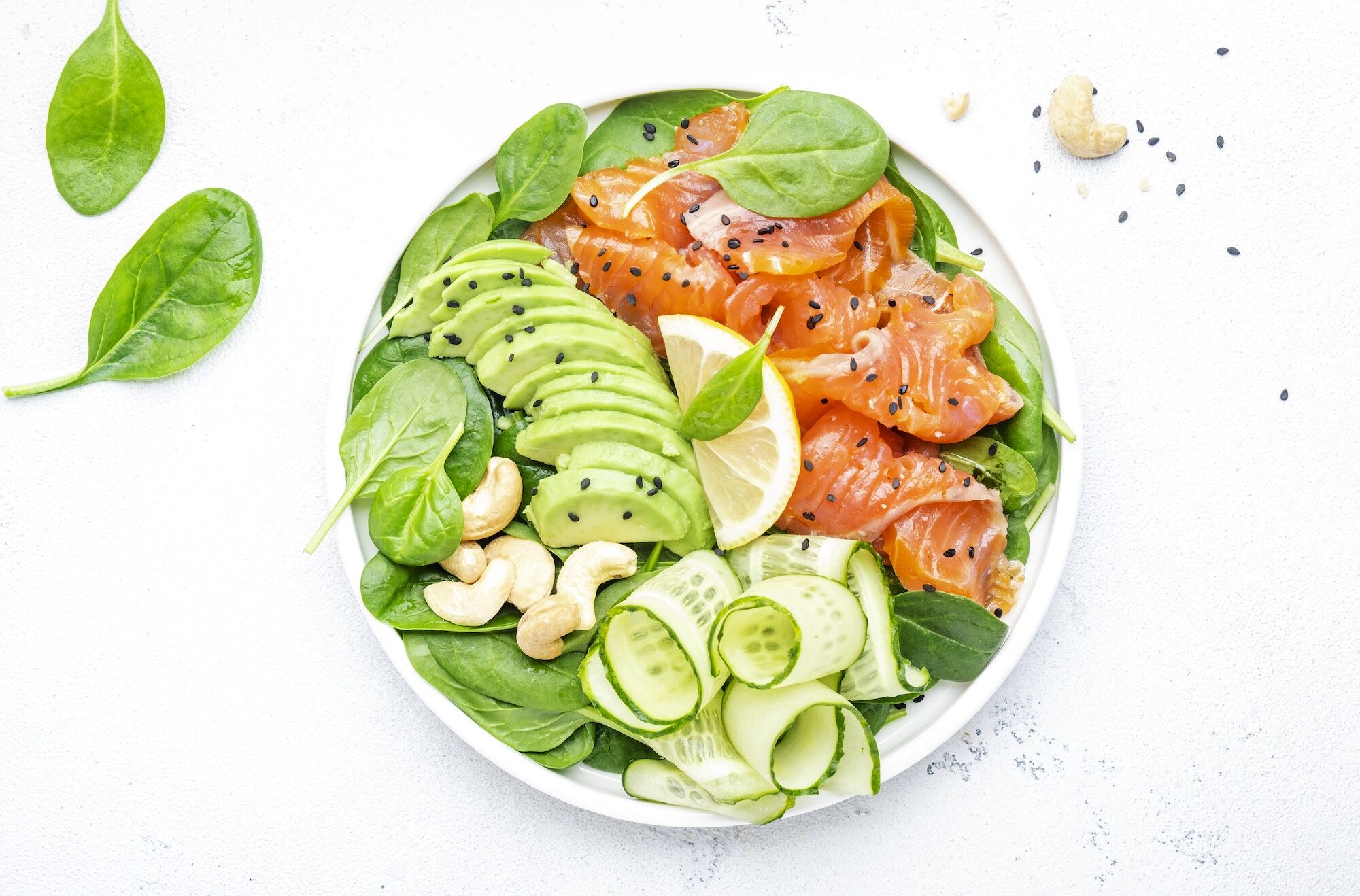 Salmon salad for ketogenic diet with avocado, spinach, cucumber, cashew nuts