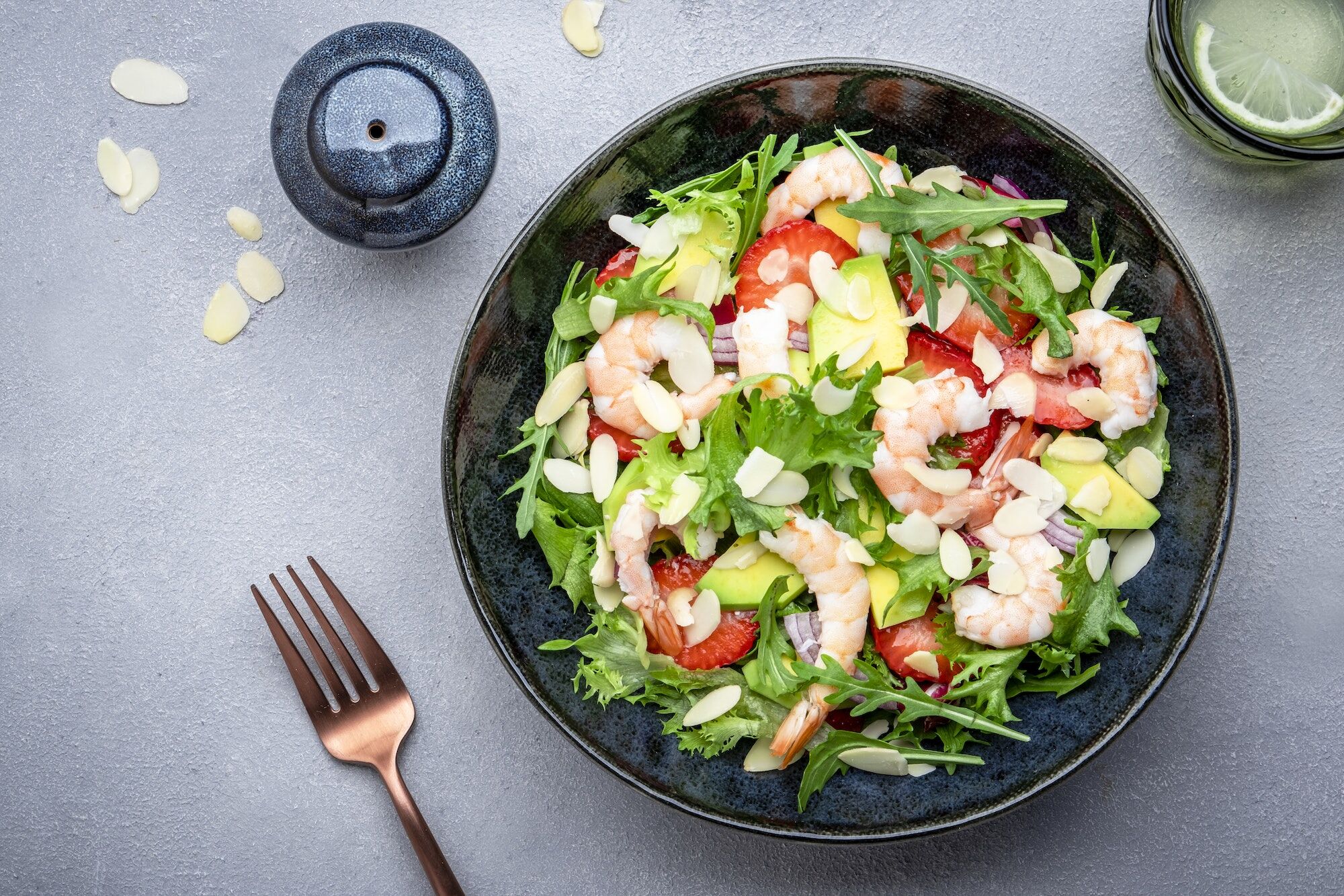 Strawberry, shrimp and herbs healthy salad with arugula, avocado and almond