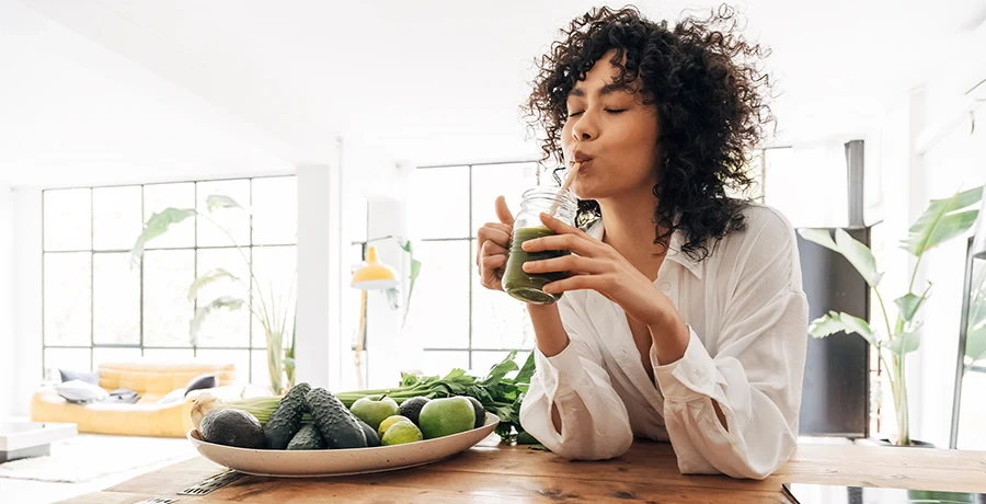High Quality Juice Cleanse Corporate Packages London Professional woman drinking green juice cleanse at modern office workspace with fresh vegetables for corporate wellness program