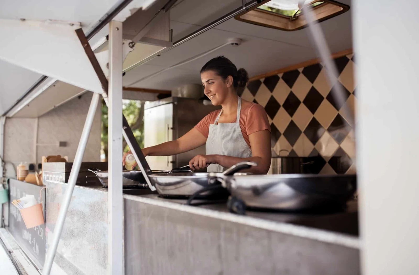 Professional female chef cooking in mobile food truck kitchen for Pearl Lemon Catering exceptional service Barcelona