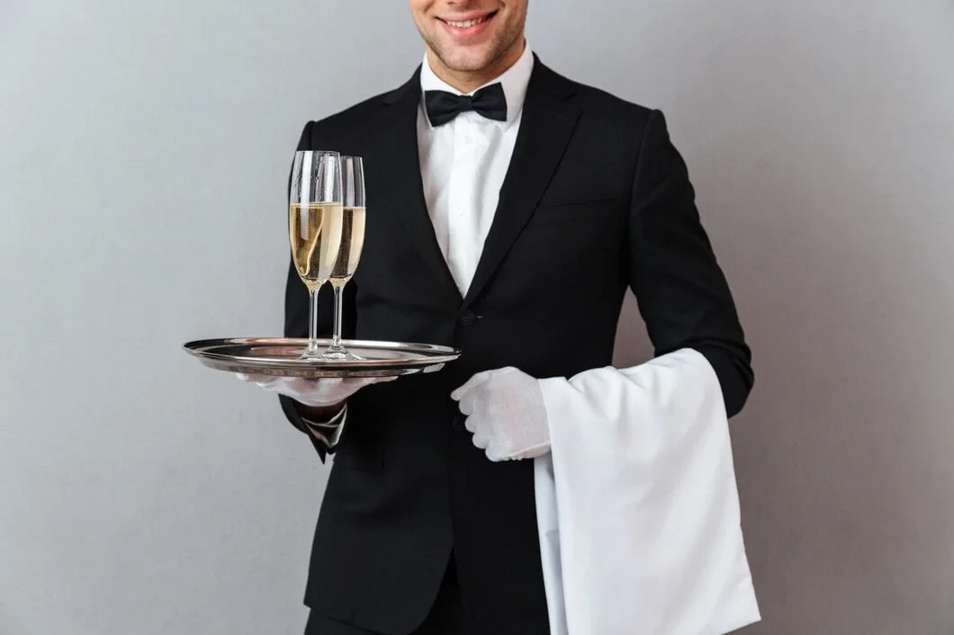 Professional waiter in formal tuxedo serving champagne for Corporate Catering Services in Zurich, Switzerland with premium hospitality