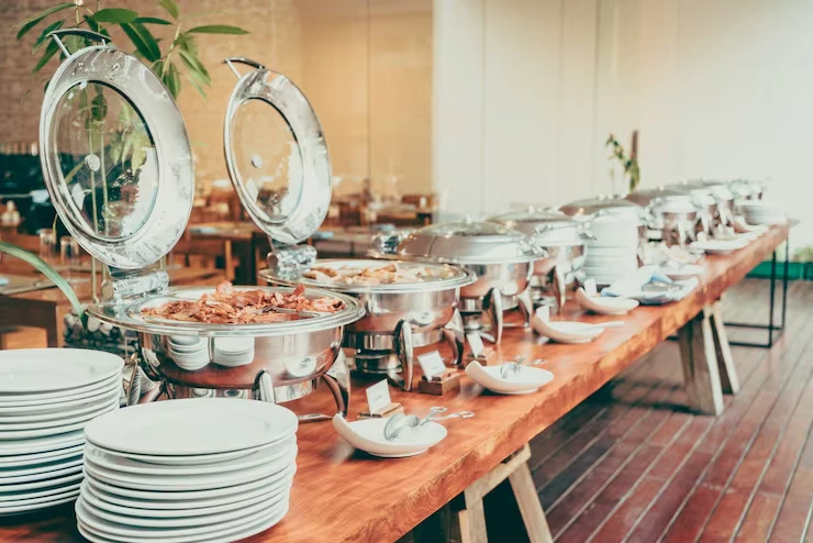 Professional buffet setup with chafing dishes and stacked plates ready for corporate event service