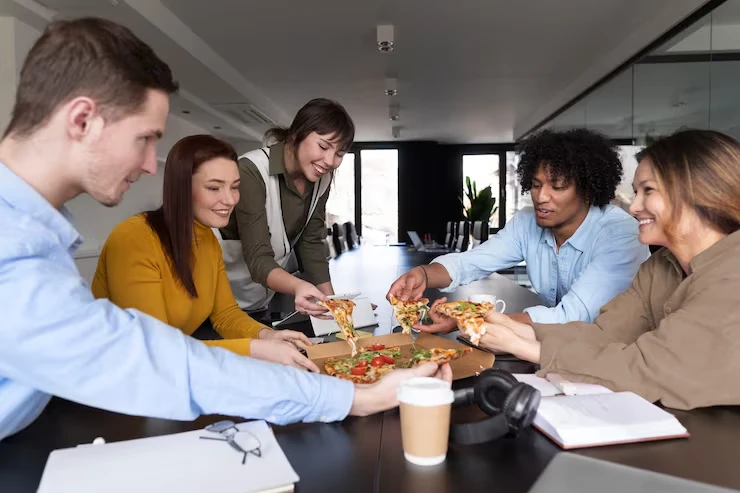 Business team sharing pizza during working lunch meeting in modern Stockholm office conference room