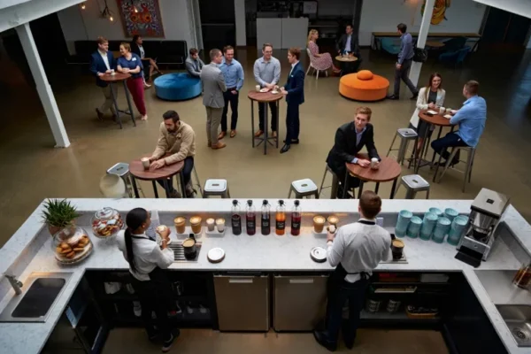 Baristas preparing specialty coffee for guests during a modern corporate coffee break event featuring interactive stations and small group seating.