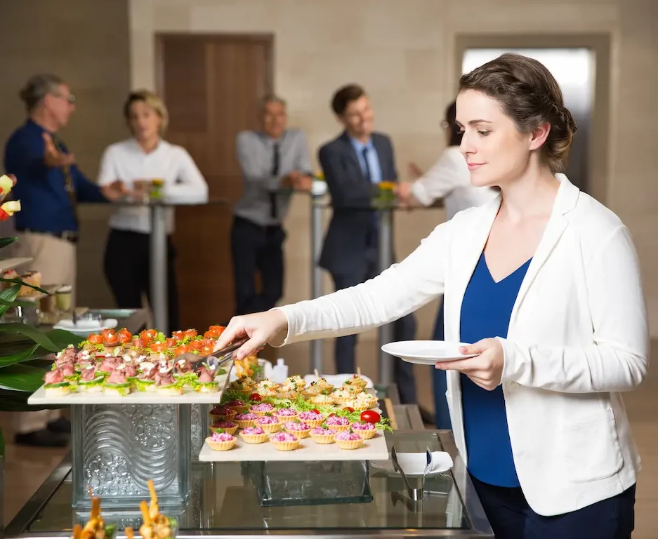 Woman selecting appetizers from a catered buffet during a business conference or seminar.