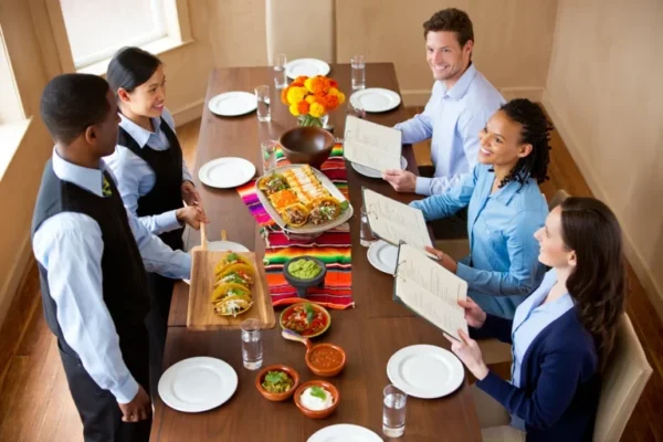 A catering team presenting a selection of Mexican dishes to a group of professionals reviewing menu options during an event-ready Mexican menu planning session.