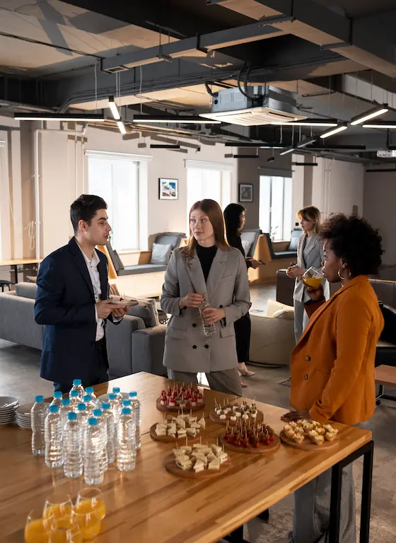 Employees enjoying catered snacks and drinks during a team-building event in a modern office space.