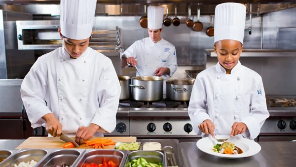 Chefs preparing Italian dishes in a modern, upscale kitchen as part of a professional catering team.