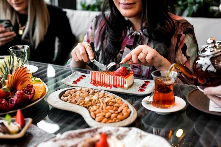 Woman cutting strawberry cheesecake at catered table