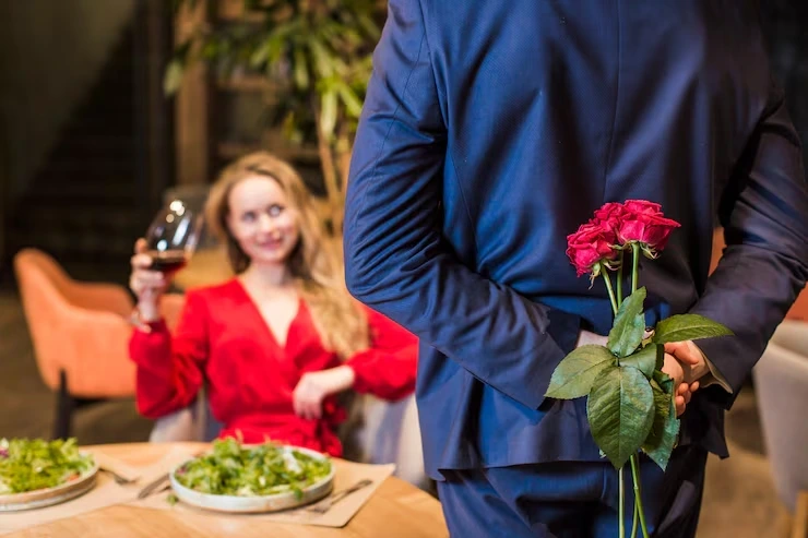 Waiter holding roses behind back for dining guest
