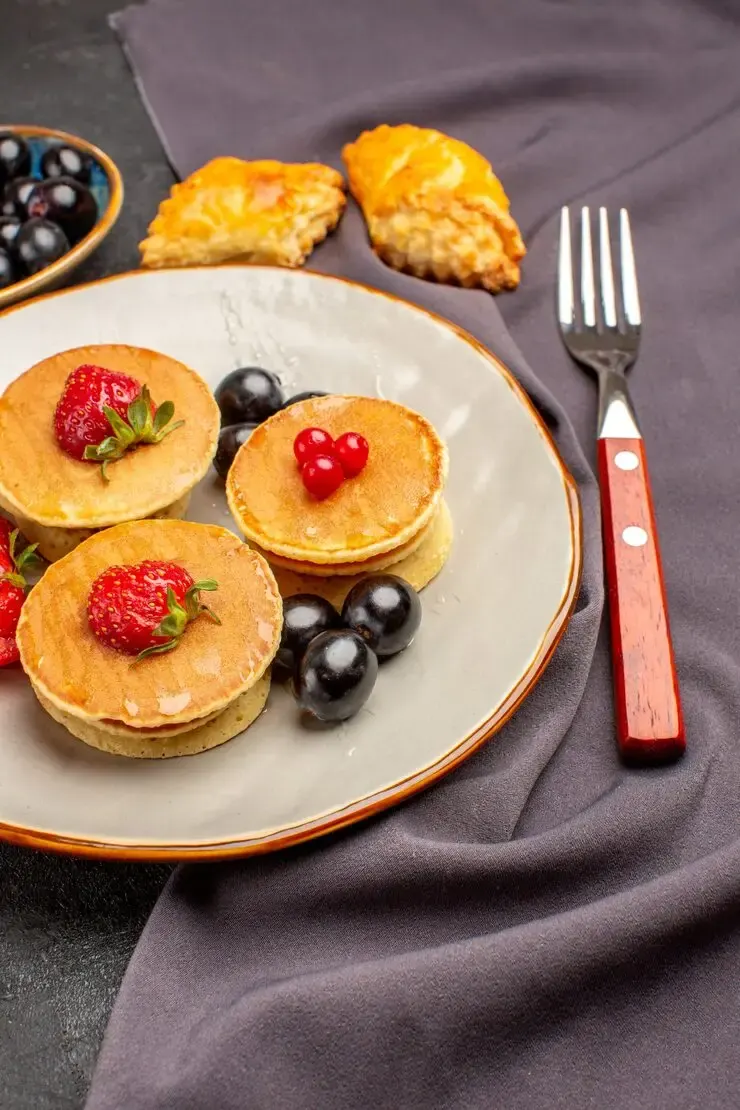 Pancakes with strawberries and dark cherries on plate