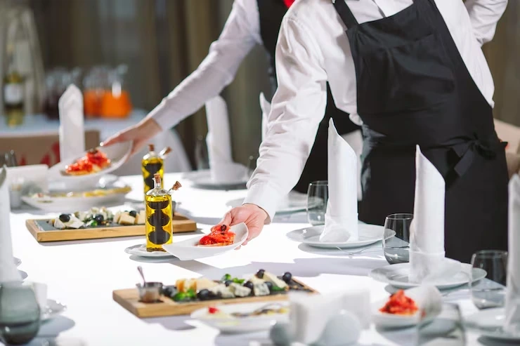 Catering staff arranging plates on event dining table