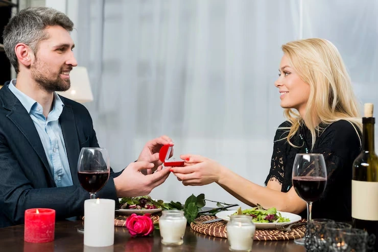 Man presenting gift box to woman at dinner table