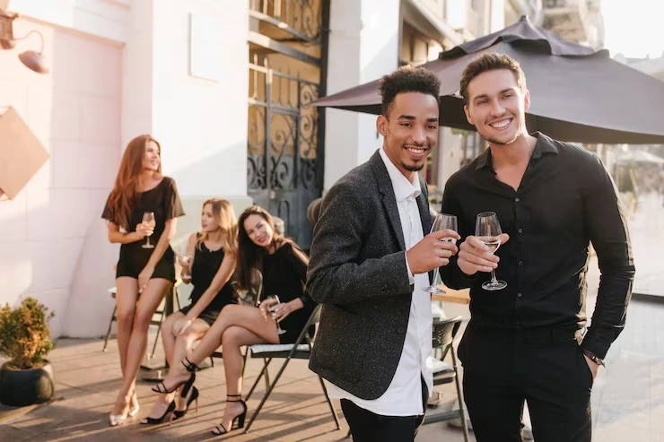 Two men with champagne at outdoor event with guests