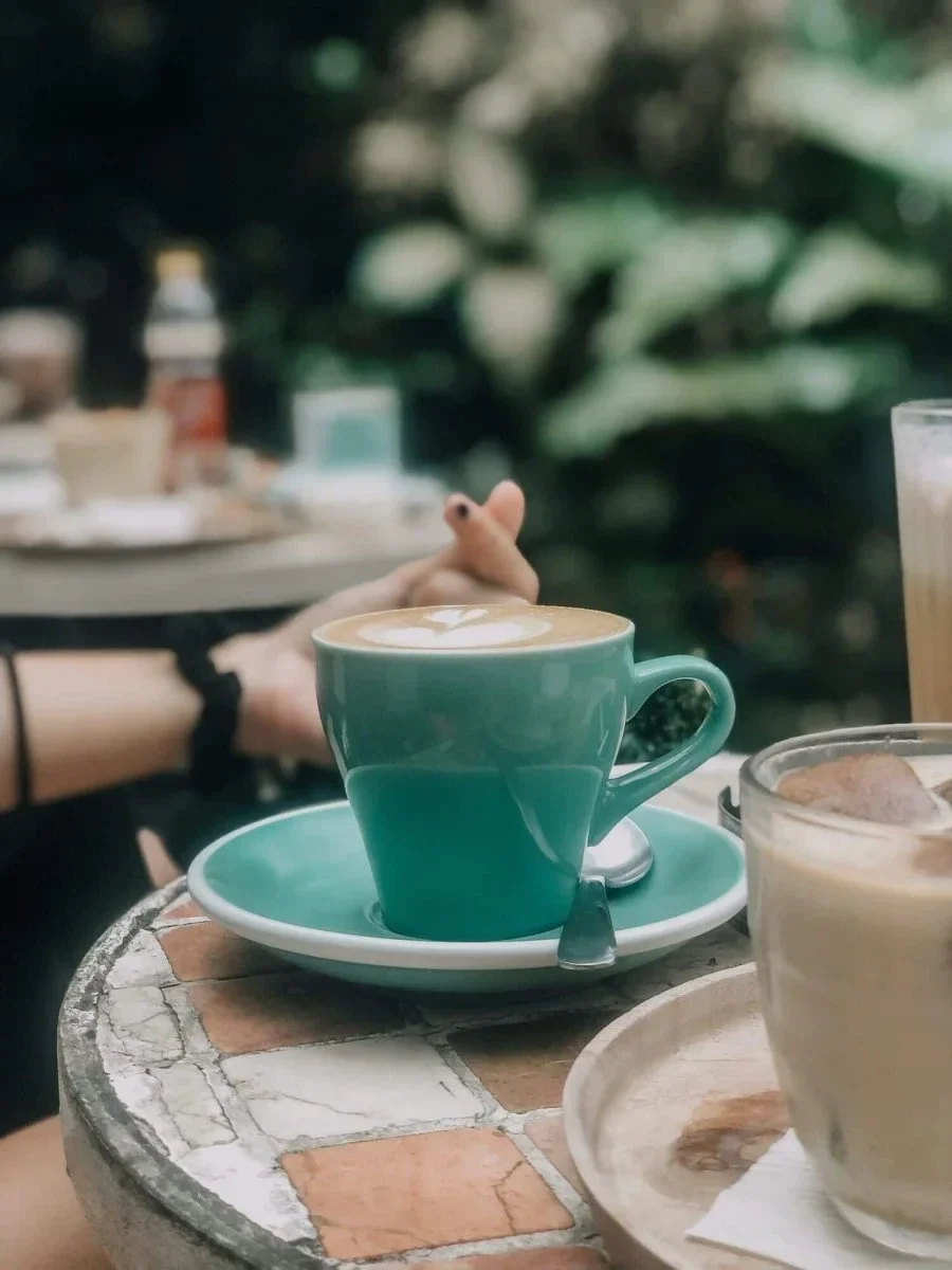 Premium coffee catering for events in London featuring turquoise cup with latte art on rustic wooden table with outdoor ambiance