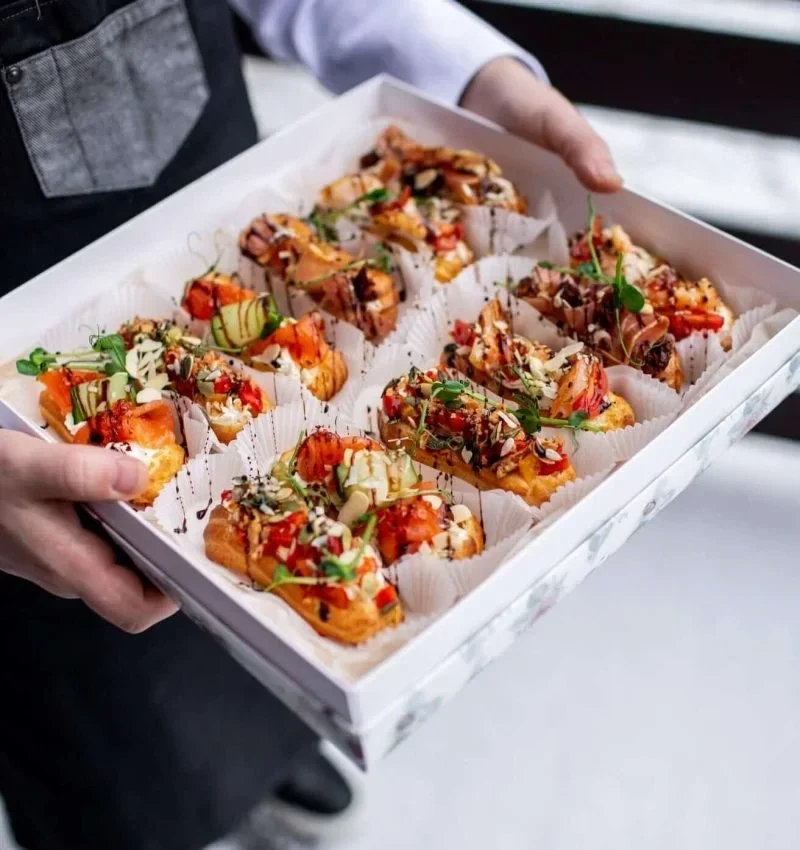 Premium coffee catering for events in London showcasing artisan appetizers with fresh herbs and colorful toppings being delivered by catering staff