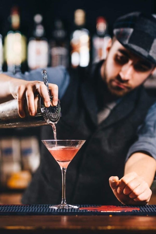 Portrait of vintage barman workin in bar. Pouring and preparing cocktails